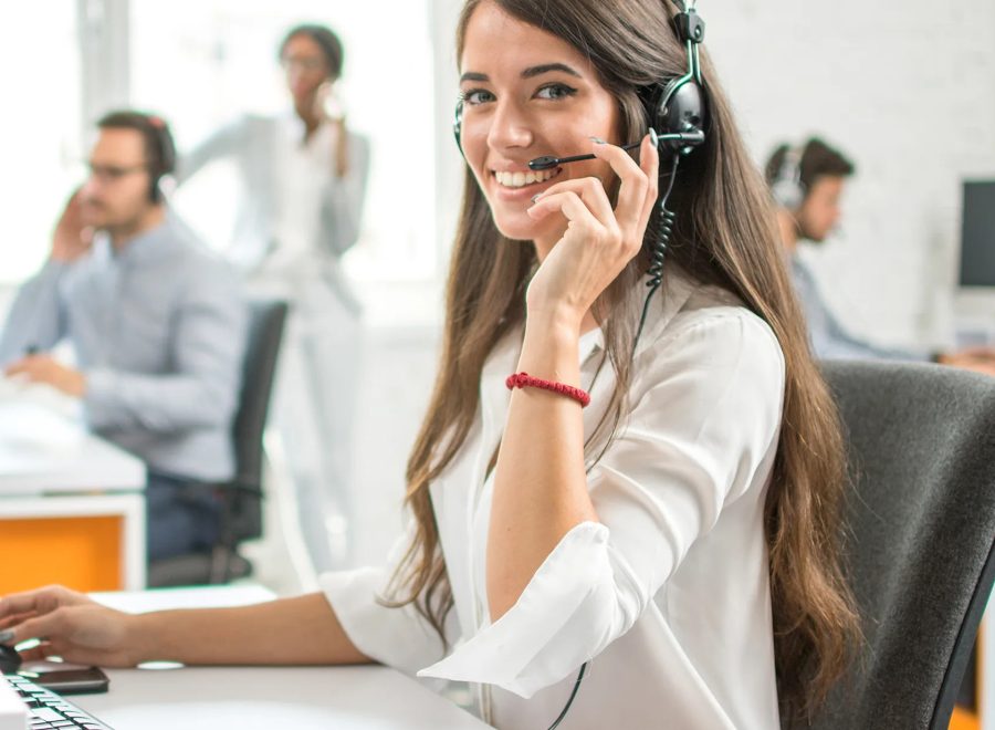 Young friendly operator woman agent with headsets working in a call centre.